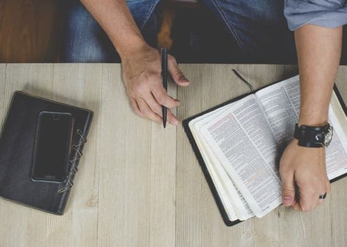 person-holding-bible-with-pen